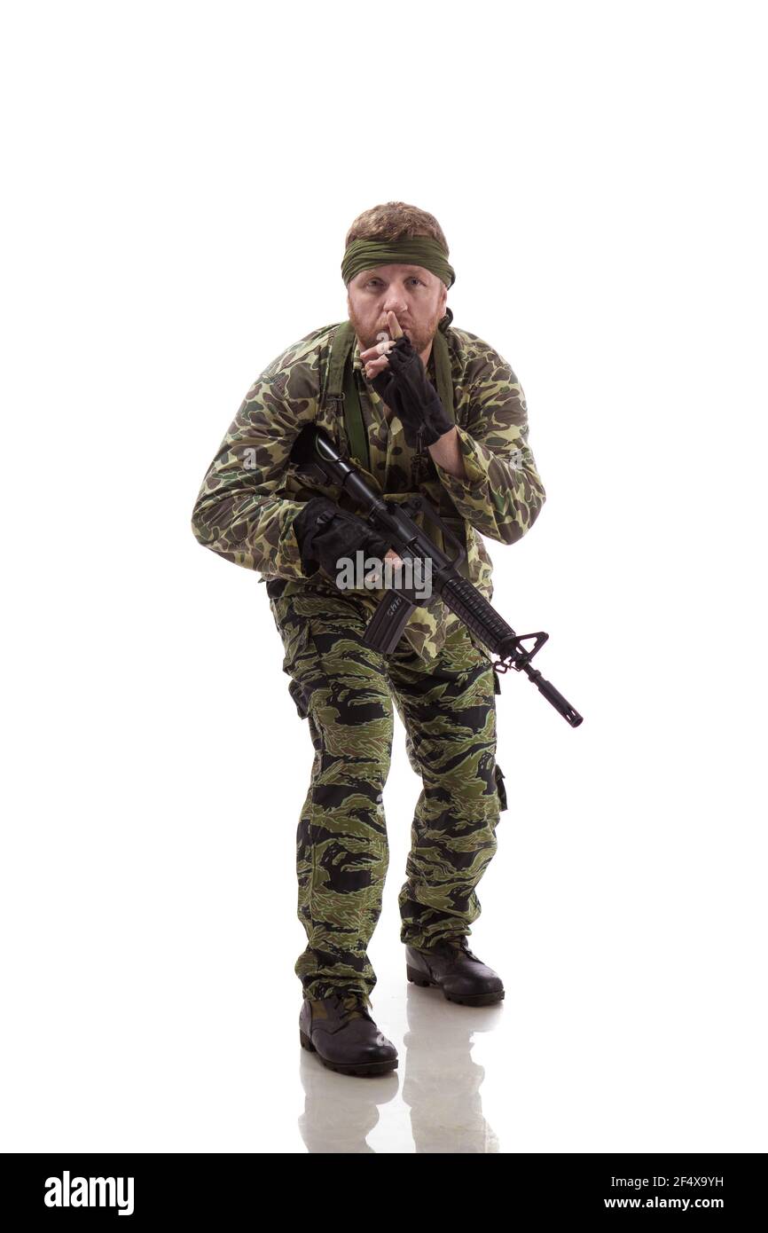 Man actor in the form of an American fur seal posing with a machine gun in his hands on a white background. Special Forces in Vietnam, 1970's. Stock Photo