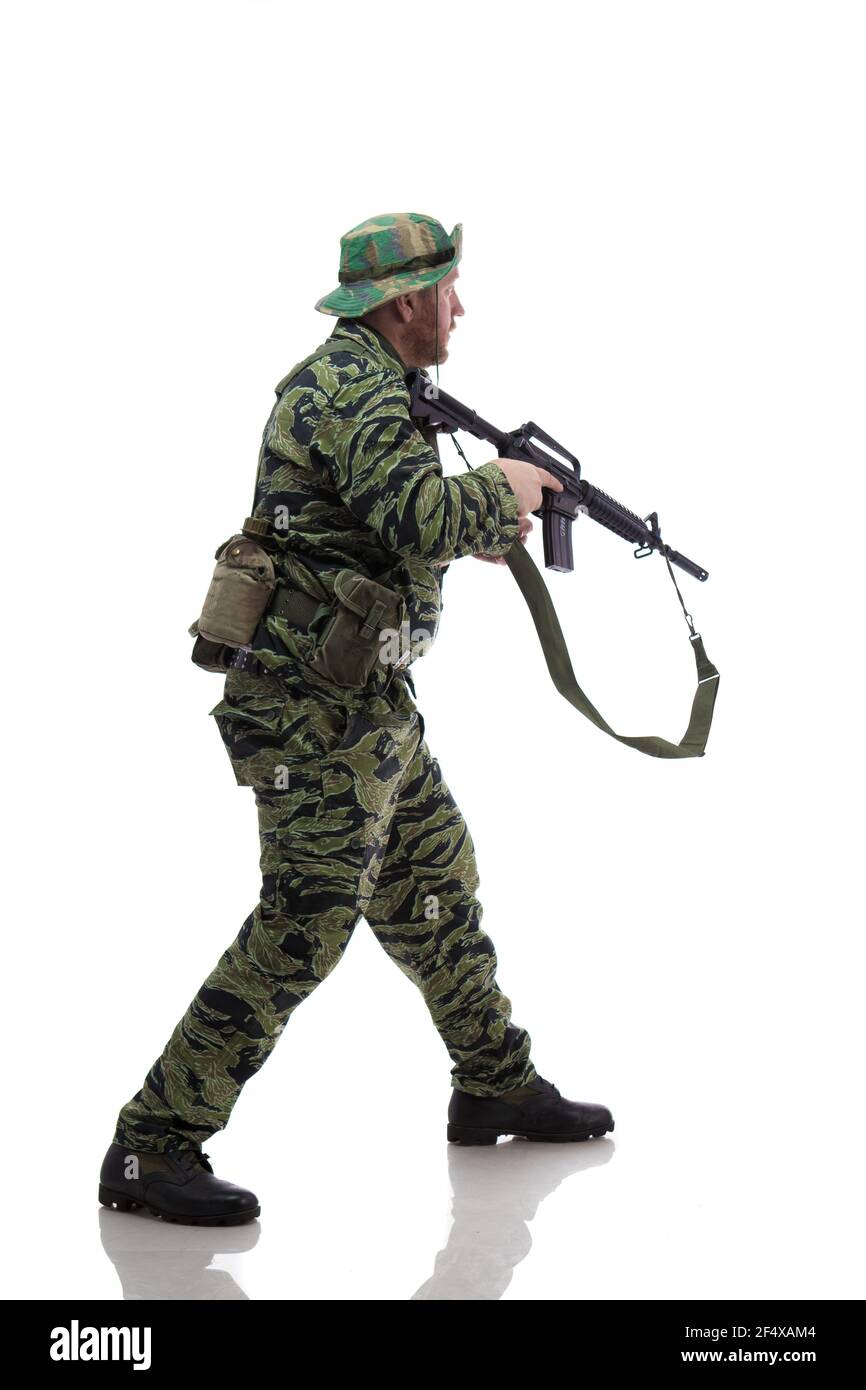 Man actor in the form of an American fur seal posing with a machine gun in his hands on a white background. Special Forces in Vietnam, 1970's. Stock Photo