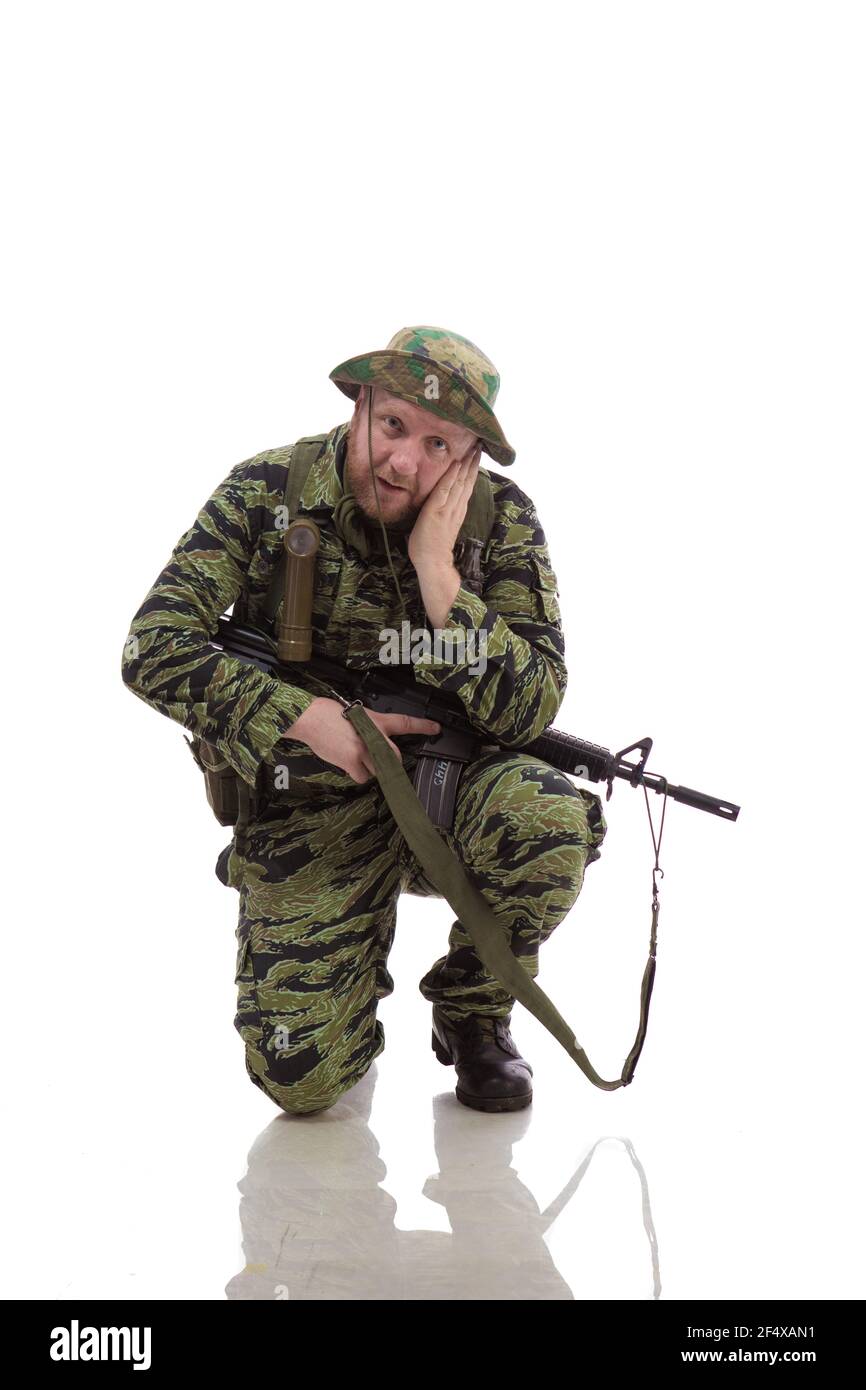 Man actor in the form of an American fur seal posing with a machine gun in his hands on a white background. Special Forces in Vietnam, 1970's. Stock Photo