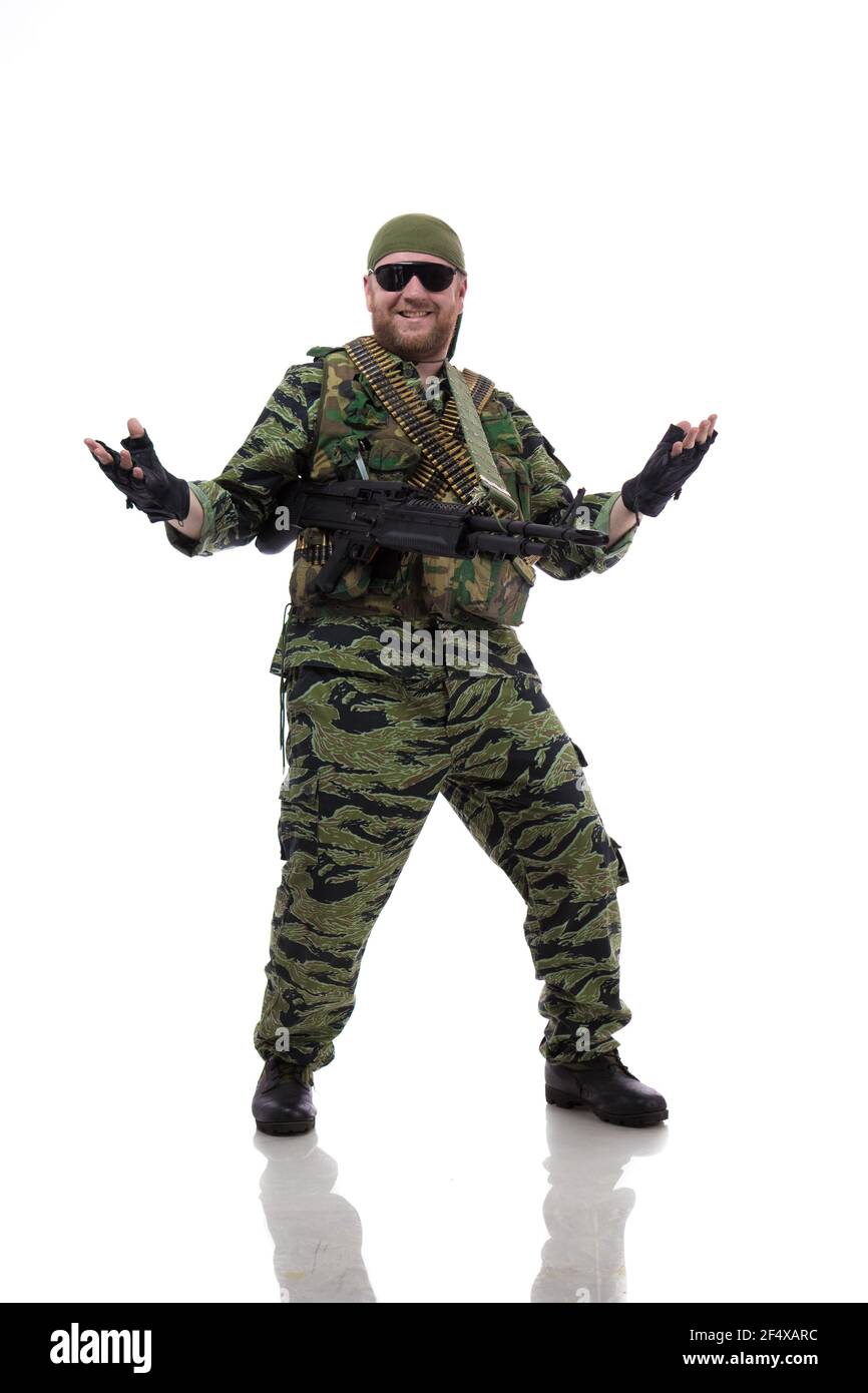 Man actor in the form of an American fur seal posing with a machine gun in his hands on a white background. Special Forces in Vietnam, 1970's. Stock Photo