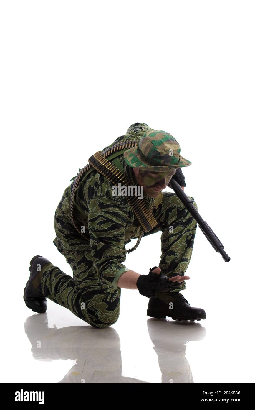 Man actor in the form of an American fur seal posing with a machine gun in his hands on a white background. Special Forces in Vietnam, 1970's. Stock Photo