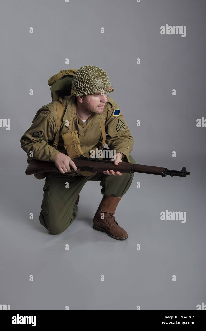 The man is an actor in the military uniform of an American ranger, wearing a helmet and with a carbine in his hands, the period of the World War II is Stock Photo