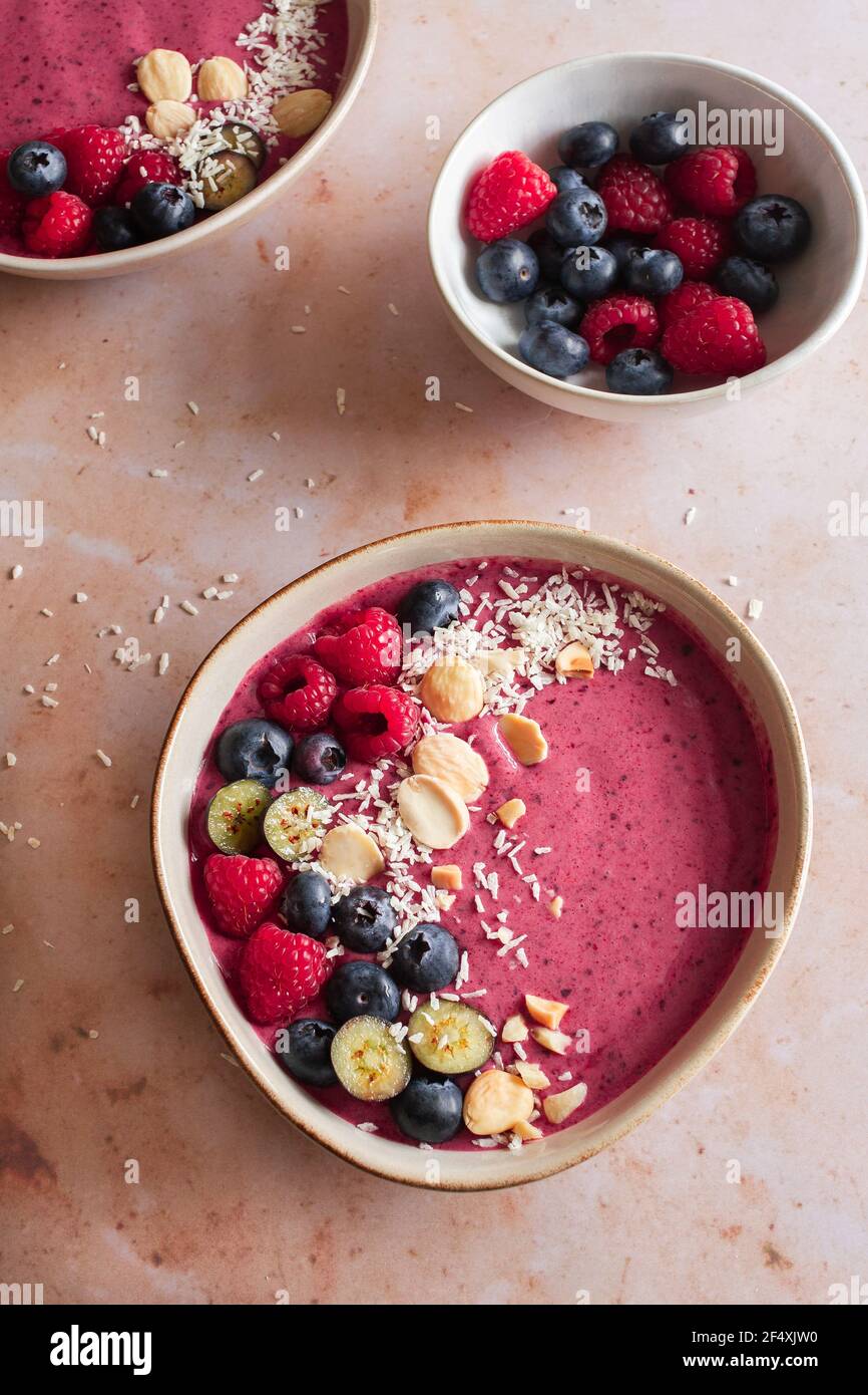 Two berry smoothie bowls with fresh raspberries and blueberries, desiccated coconut and almonds. Stock Photo