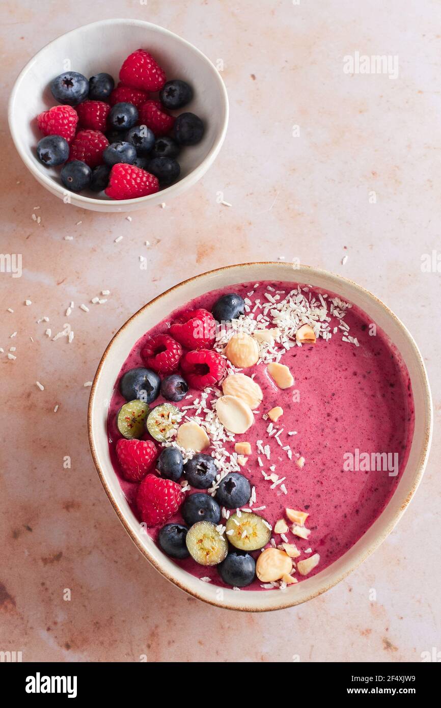 Berry smoothie bowl with fresh raspberries and blueberries, desiccated coconut and almonds. Stock Photo