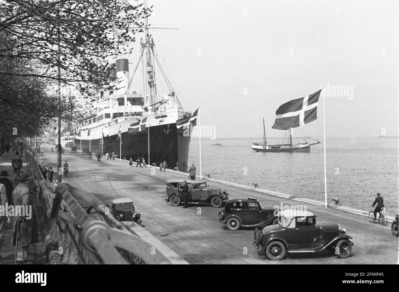 Travel photos Denmark. Copenhagen. Port. Automobiles on the quay with Danebrog. Behind the passenger ship 'Monte Rosa Stock Photo