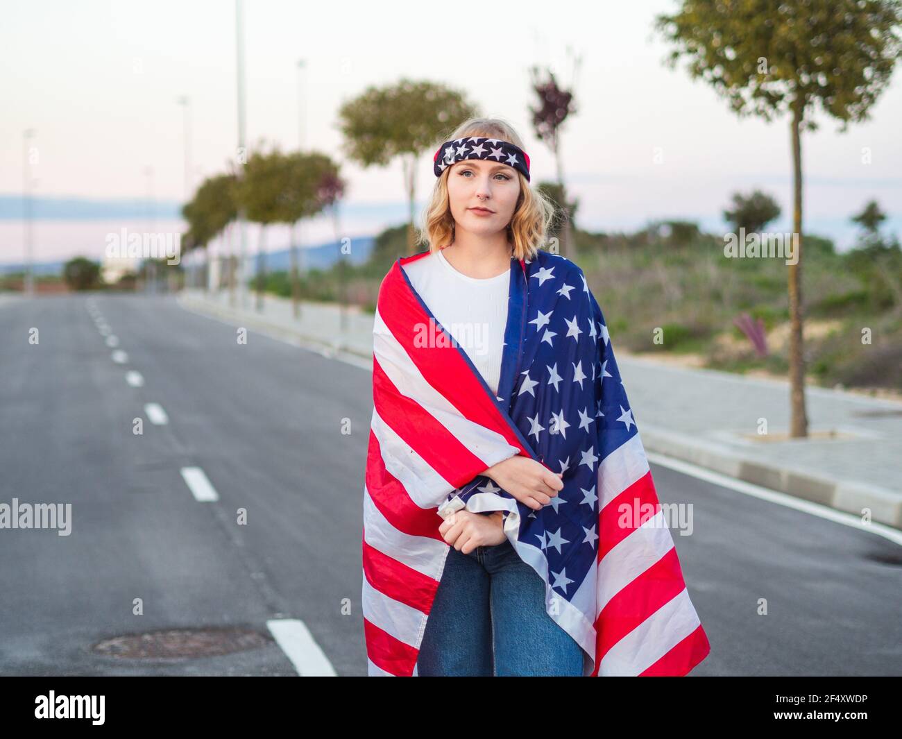 Patriotic Caucasian in the middle of the road with the US flag draped ...