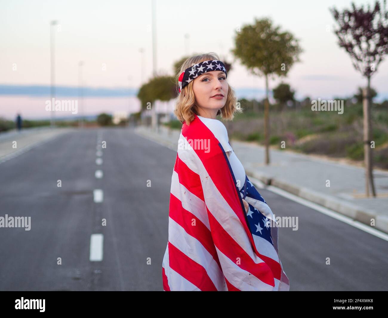 Patriotic Caucasian in the middle of the road with the US flag draped ...
