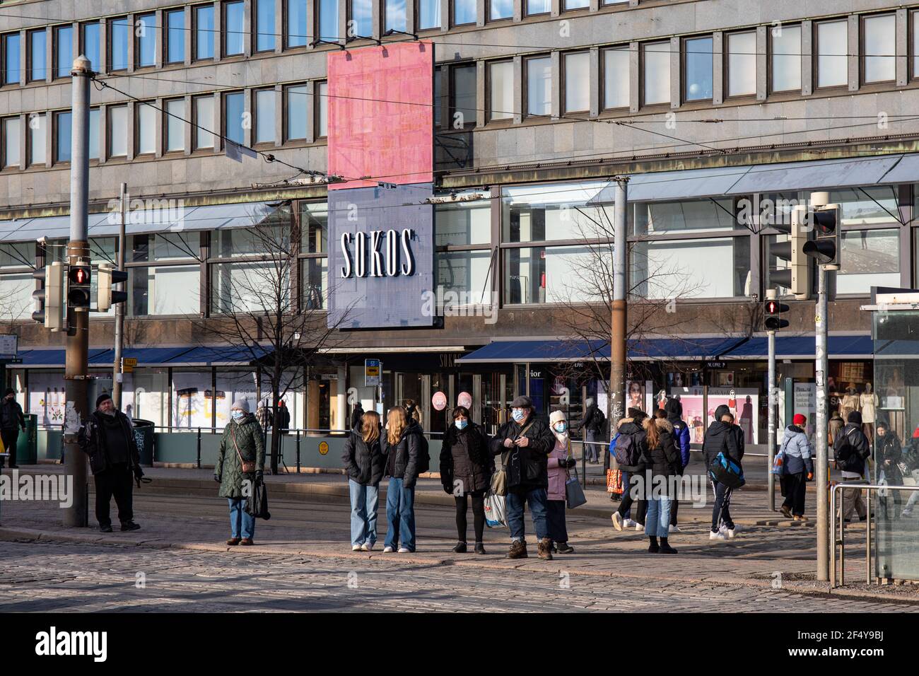 People standing at traffic lights by Mannerheimintie, Sokos department store in the background, in Helsinki, Finland. Stock Photo