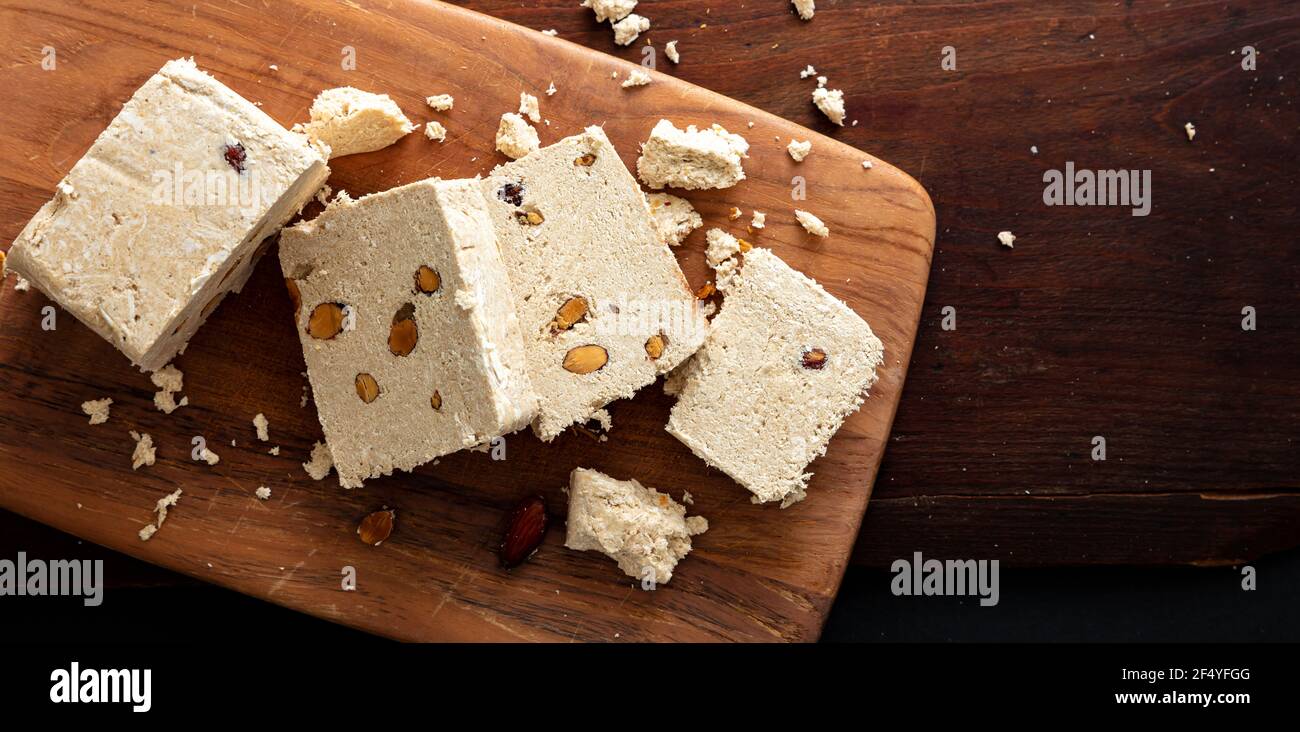 Halva tahini and almonds on wooden table background. Vanilla halvah or