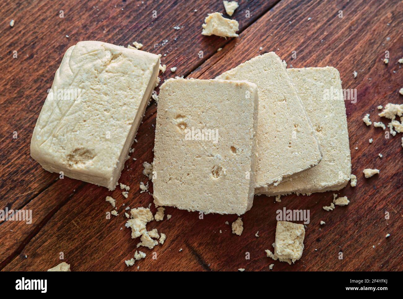 Halva sunflower seeds pieces on wooden table background, top view. Vanilla halvah or halwa, traditional dessert confection made also with sesame tahin Stock Photo
