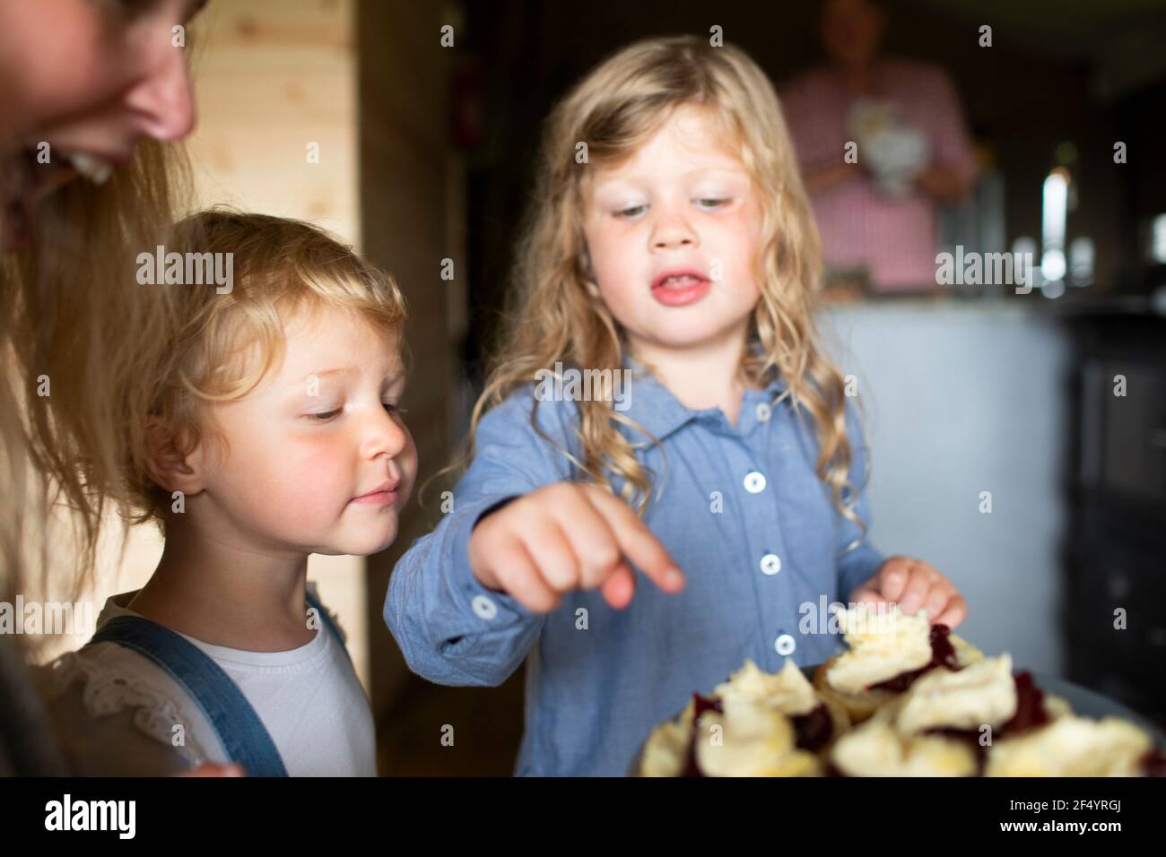Sisters looking at sweet pastries on plate Stock Photo
