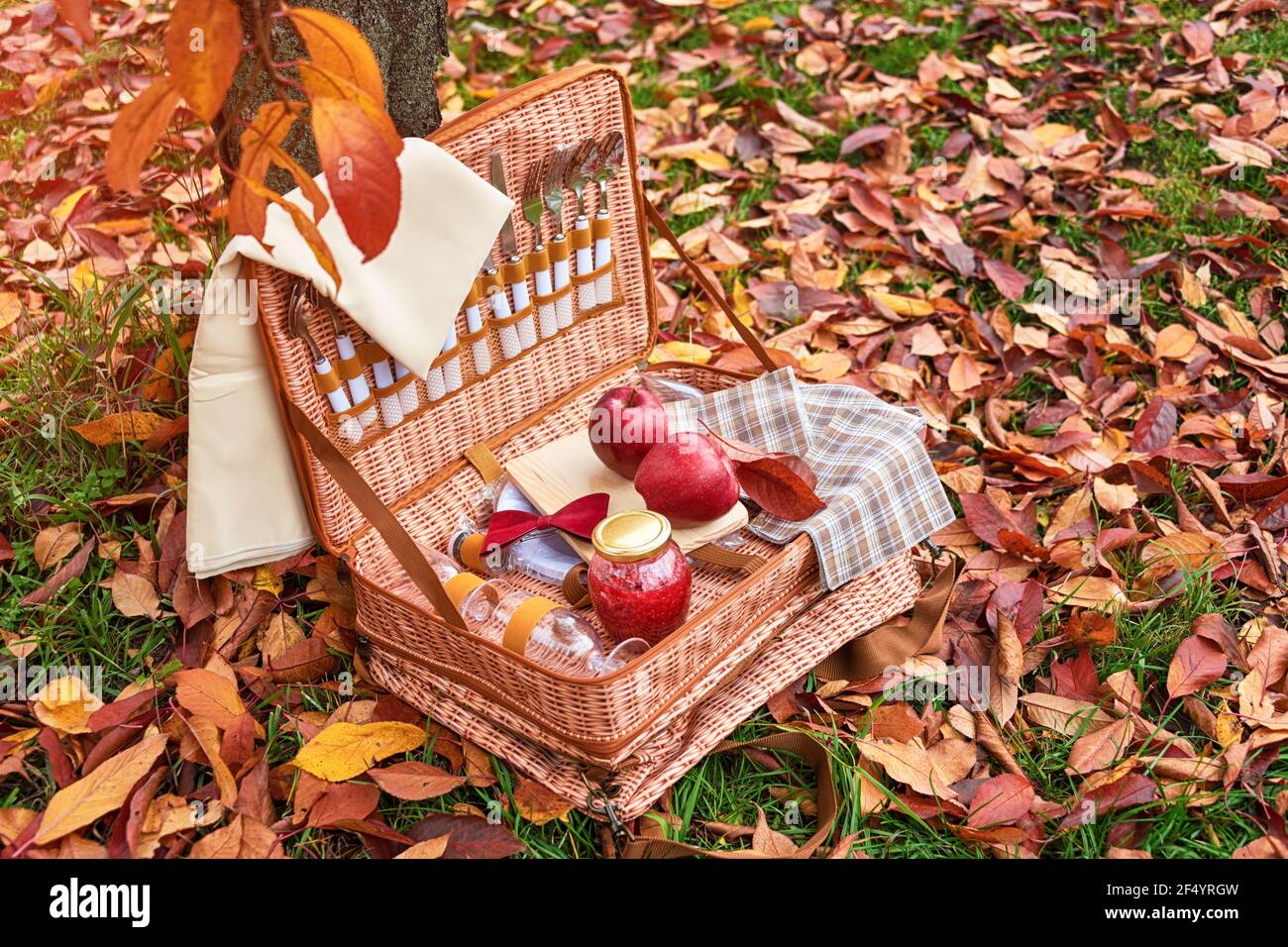 Picnic basket in autumn park. Wicker basket with apples and jar of jam on  golden autumn leaves in forest, romantic date Stock Photo - Alamy