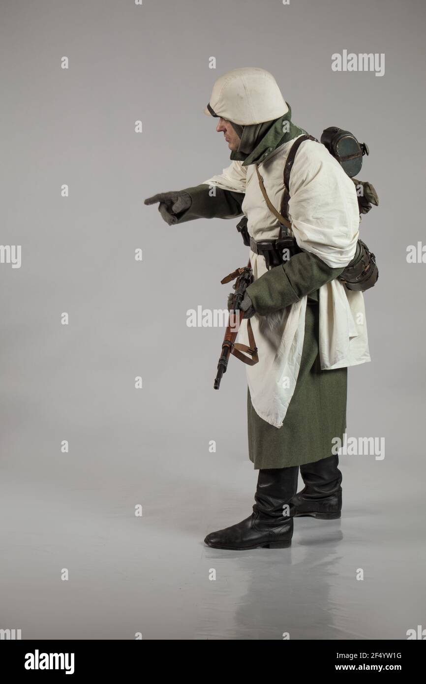 male actor in the winter military uniform of an German soldier, the period 1942, the World War II, posing on a gray background Stock Photo