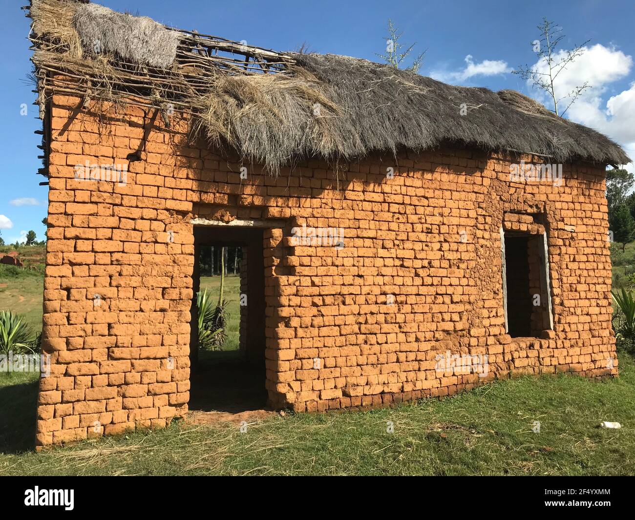 A Traditional Malagasy red clay village house with a broken roof Stock Photo