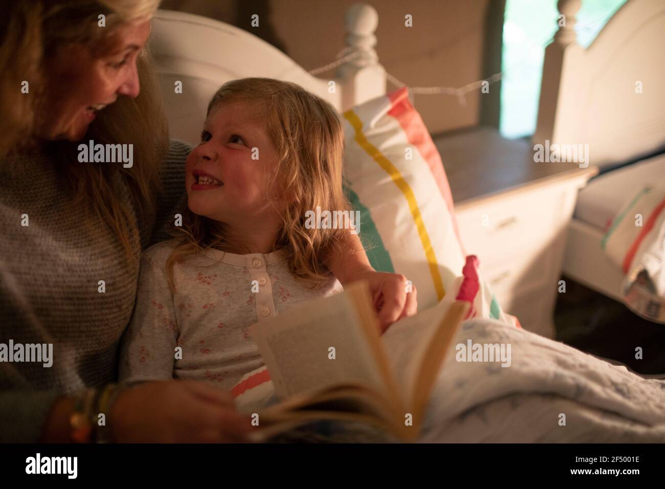 Happy mother and daughter reading bedtime story in bed Stock Photo