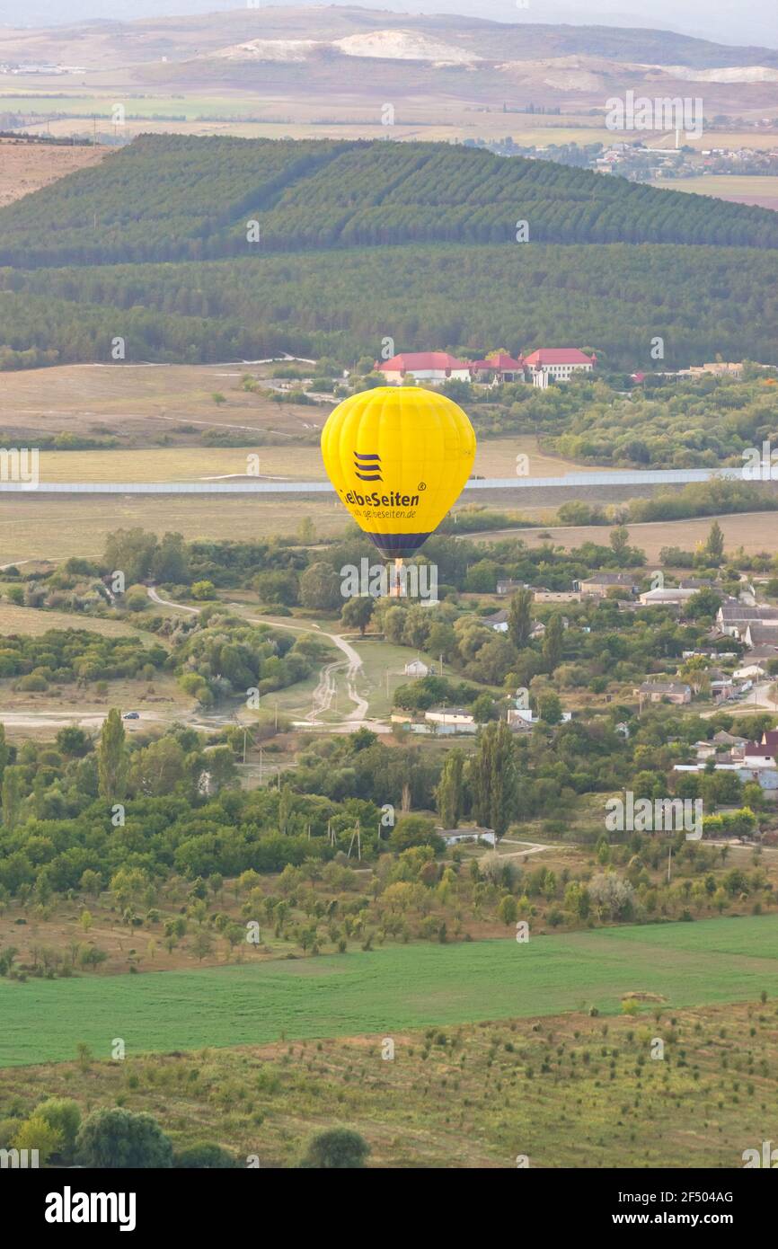 Russia, Crimea, Belogorsk September 19, 2020-A yellow GelbeSeiten balloon flies over the gardens of the village of Belaya Skala at the foot of the mou Stock Photo
