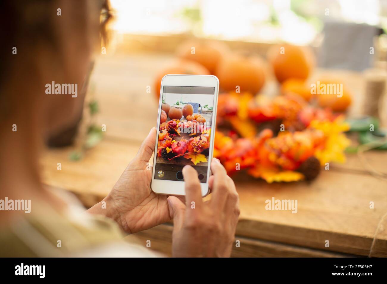 Female florist with camera phone photographing autumn display Stock Photo