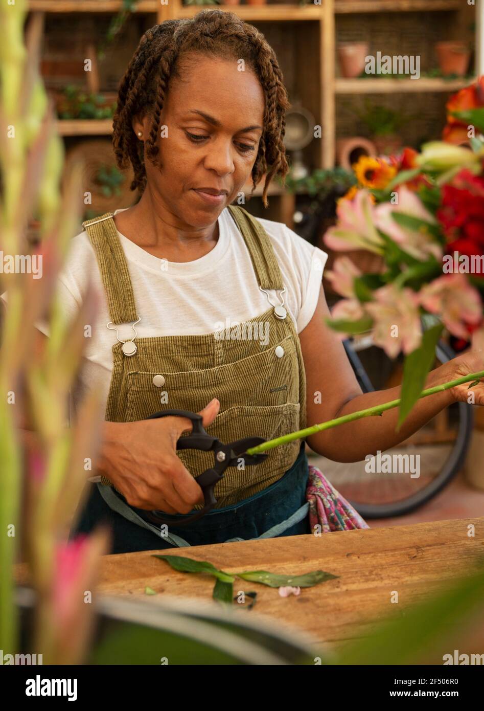 Female florist trimming flower stem in shop Stock Photo - Alamy
