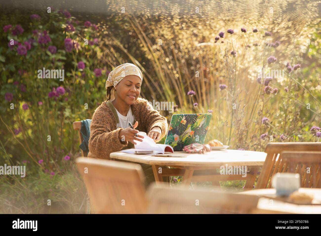 Woman working at laptop at idyllic garden cafe table Stock Photo