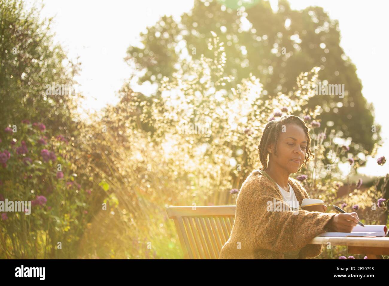 Woman working at sunny idyllic garden cafe table Stock Photo