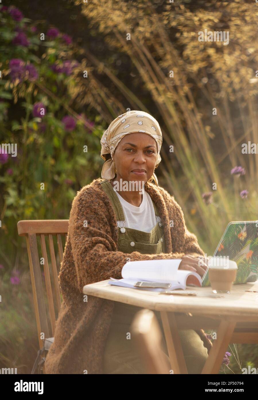 Portrait confident woman working at laptop on garden patio table Stock Photo