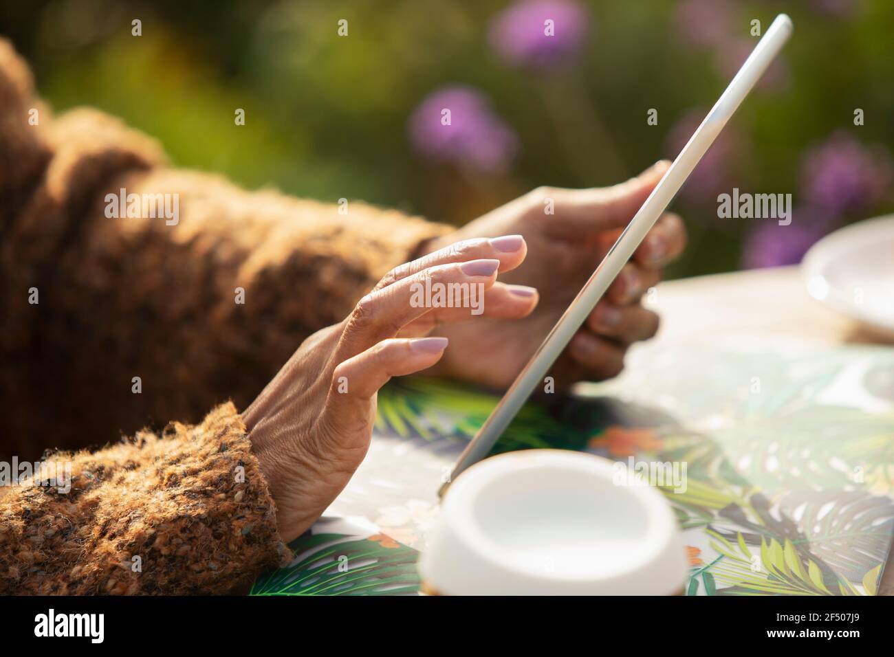 Close up woman using digital tablet at patio table Stock Photo
