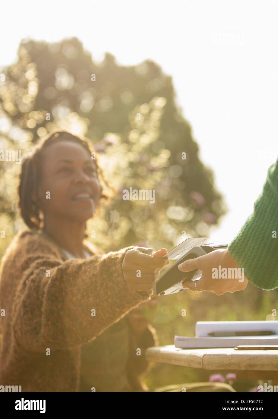 Woman paying waitress with credit card at sunny cafe Stock Photo