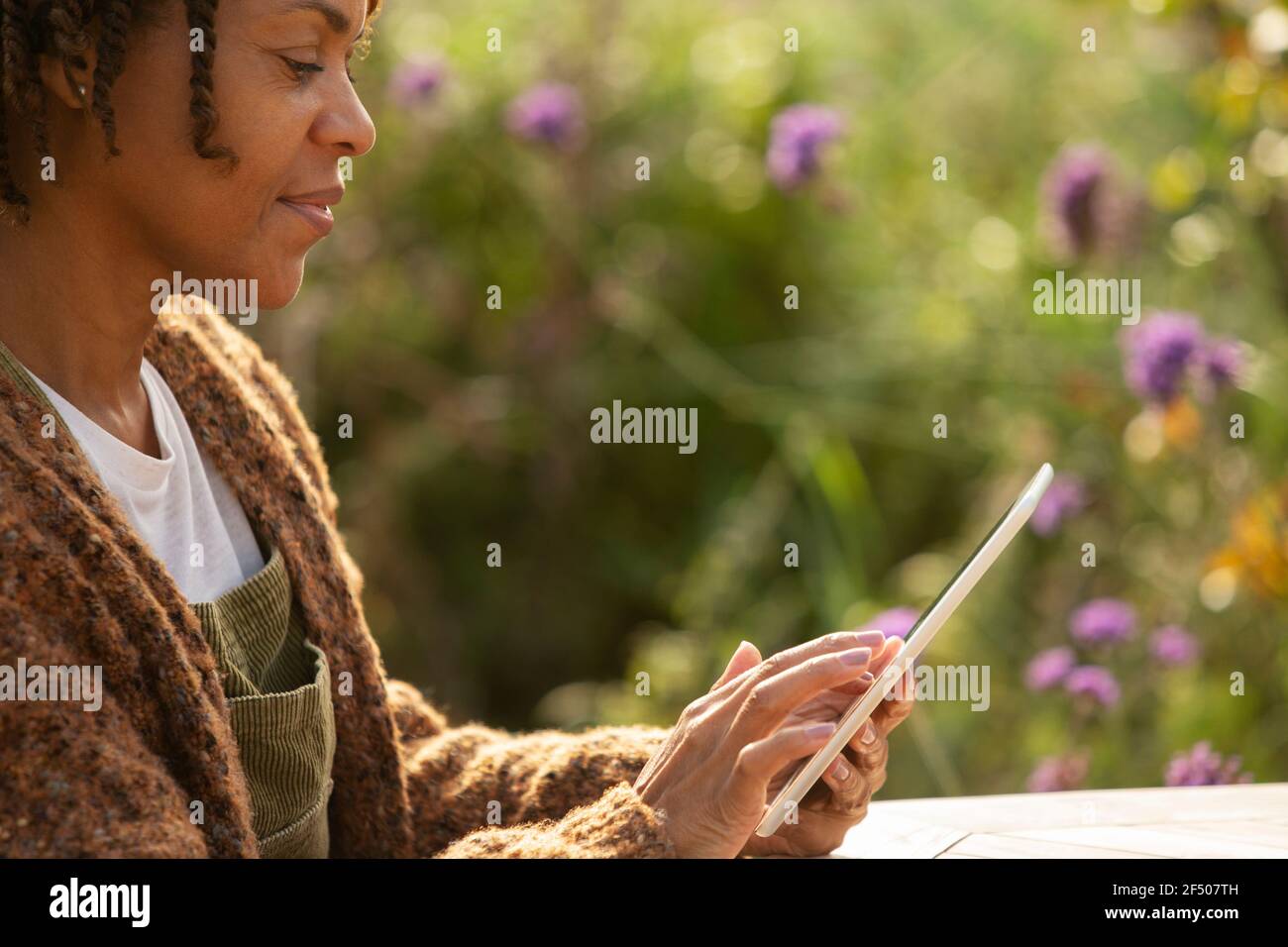 Woman using digital tablet in sunny garden Stock Photo