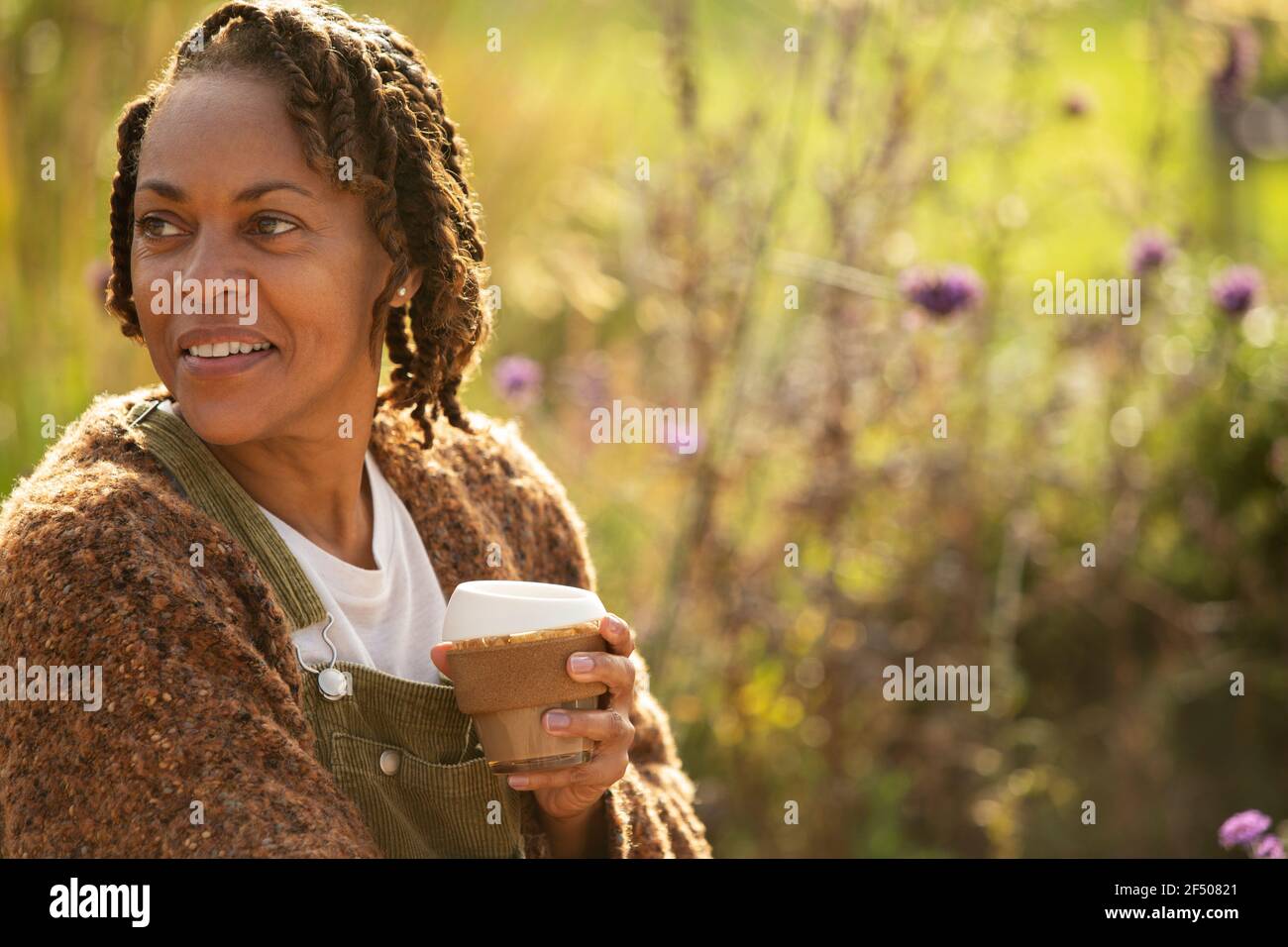 Smiling woman enjoying coffee in sunny garden Stock Photo