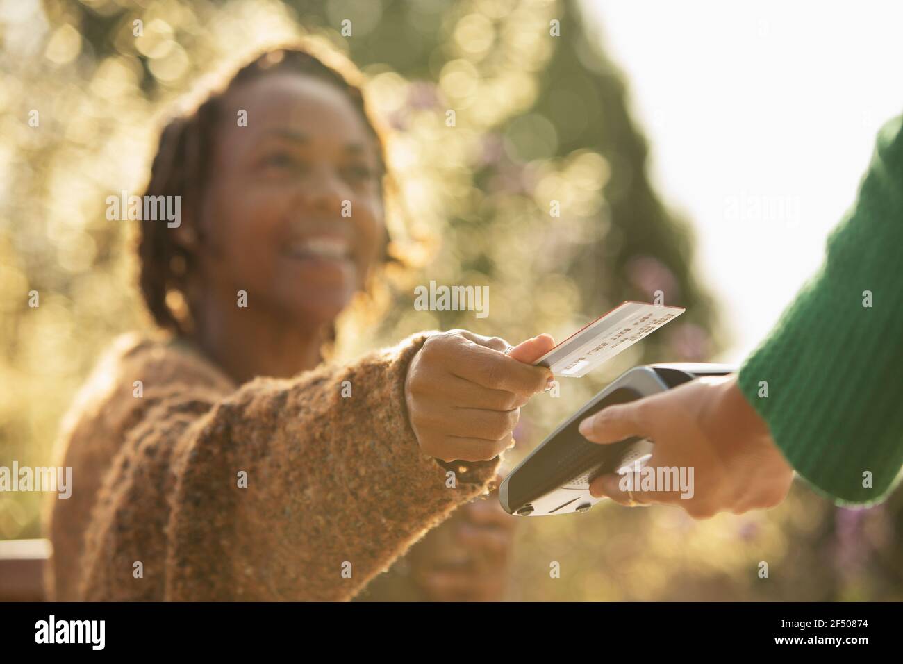 Woman paying waitress with credit card on sunny patio Stock Photo