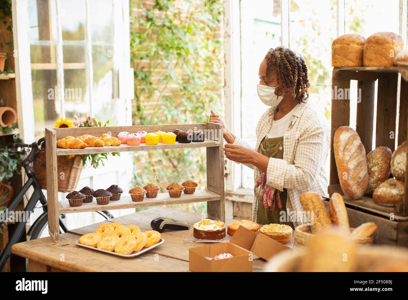 Female baker in face mask arranging pastry display in shop Stock Photo Alamy