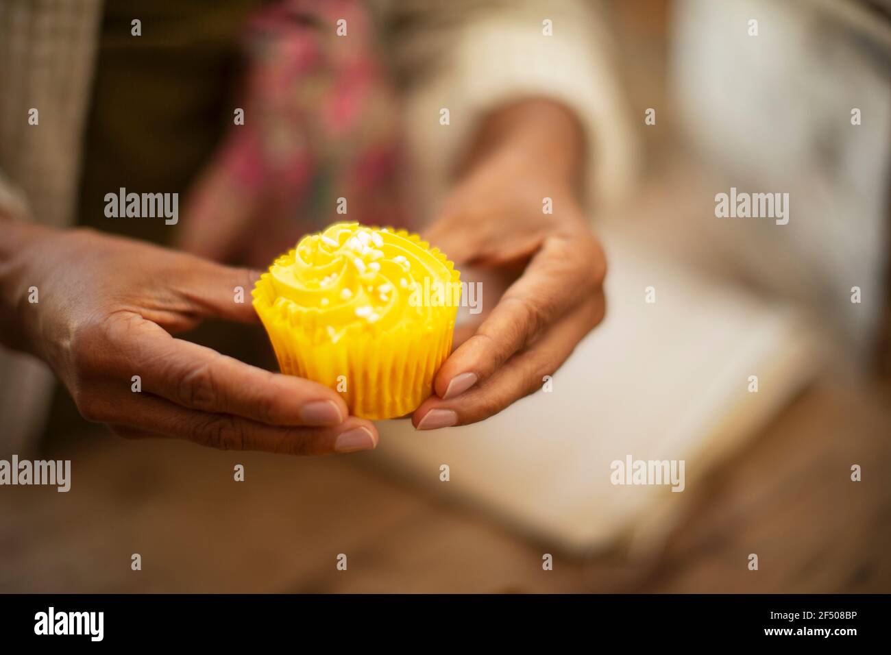 Close up woman holding bright yellow lemon cupcake Stock Photo