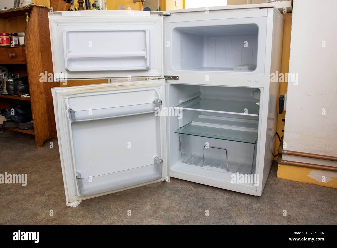 Used and empty under counter fridge freezer with doors open Stock Photo