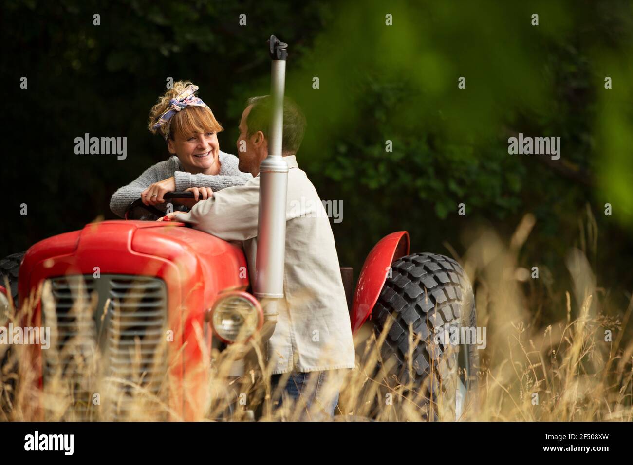 Happy couple at tractor in orchard Stock Photo