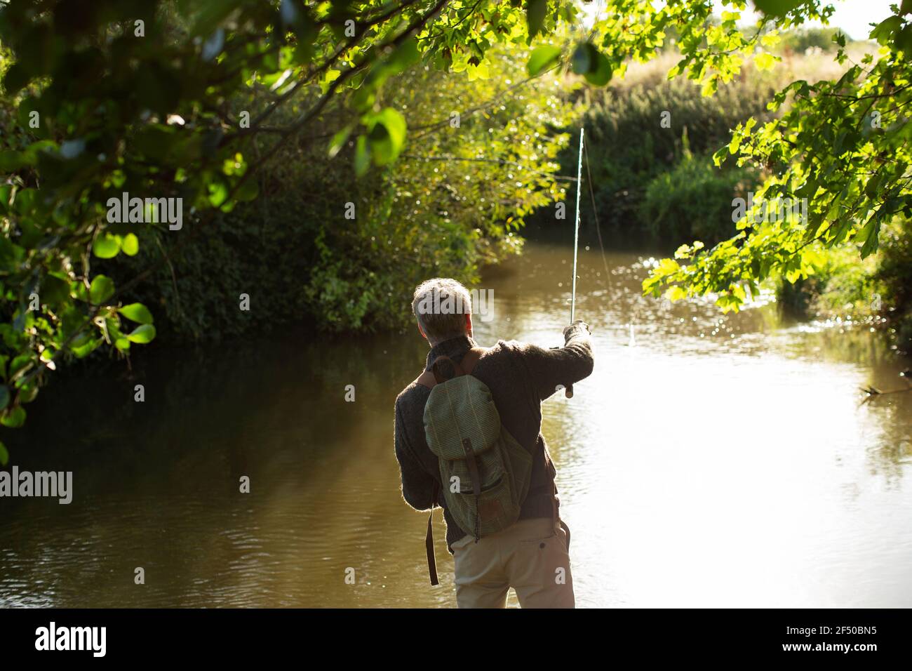 Man casting fly fishing line at sunny river Stock Photo