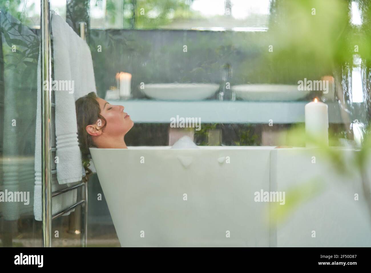 Serene woman enjoying bubble bath in modern luxury bathroom Stock Photo