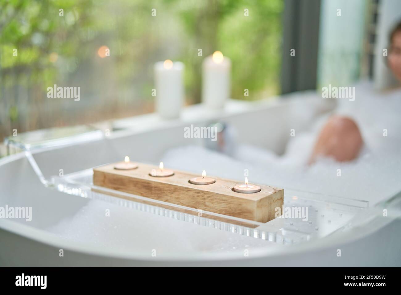 Tea light candles on tray over bubble bath Stock Photo