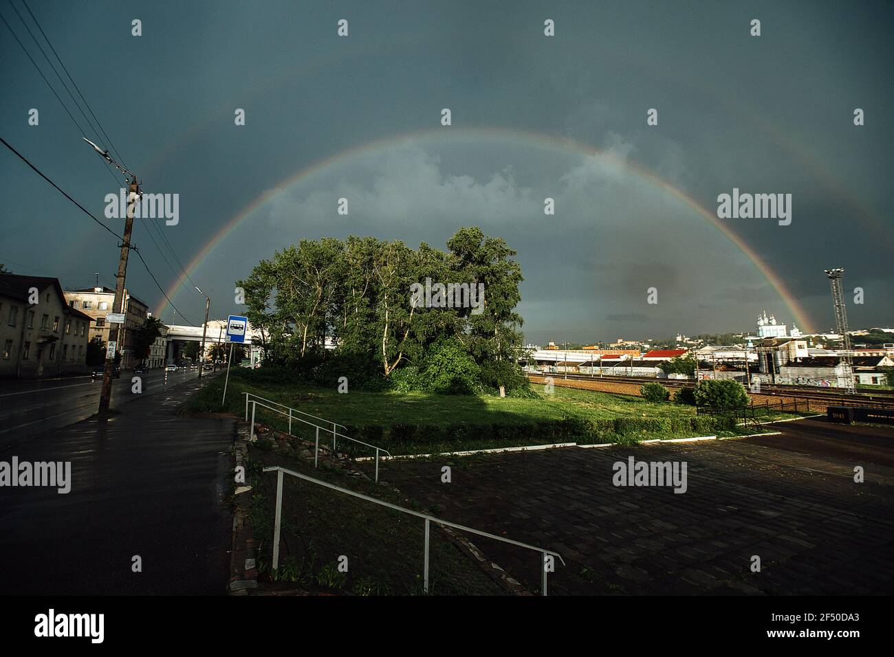 rainbow in the sky over the city after the rain. an old steam locomotive stands at the railway station Stock Photo