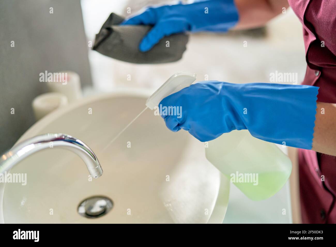 Close up hotel maid in gloves spray cleaning bathroom sink Stock Photo