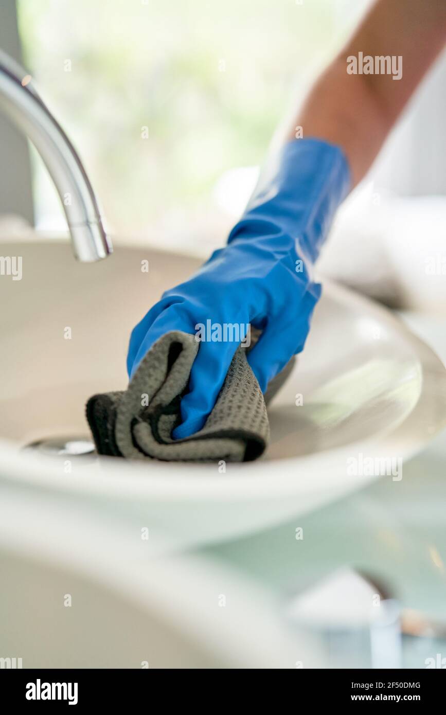 Hotel maid in gloves cleaning hotel room bathroom sink Stock Photo