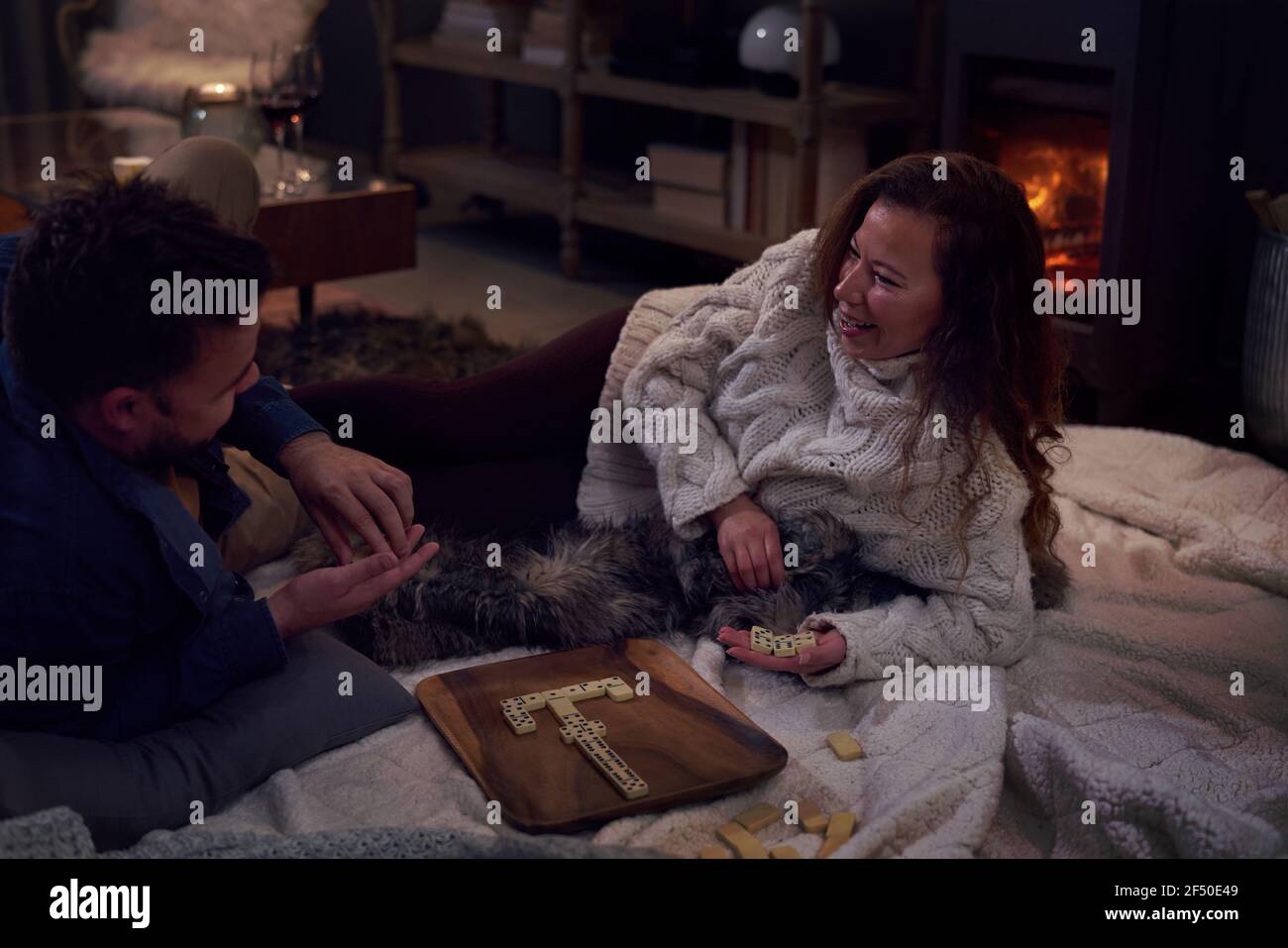 Couple playing dominoes on blanket at fireside Stock Photo