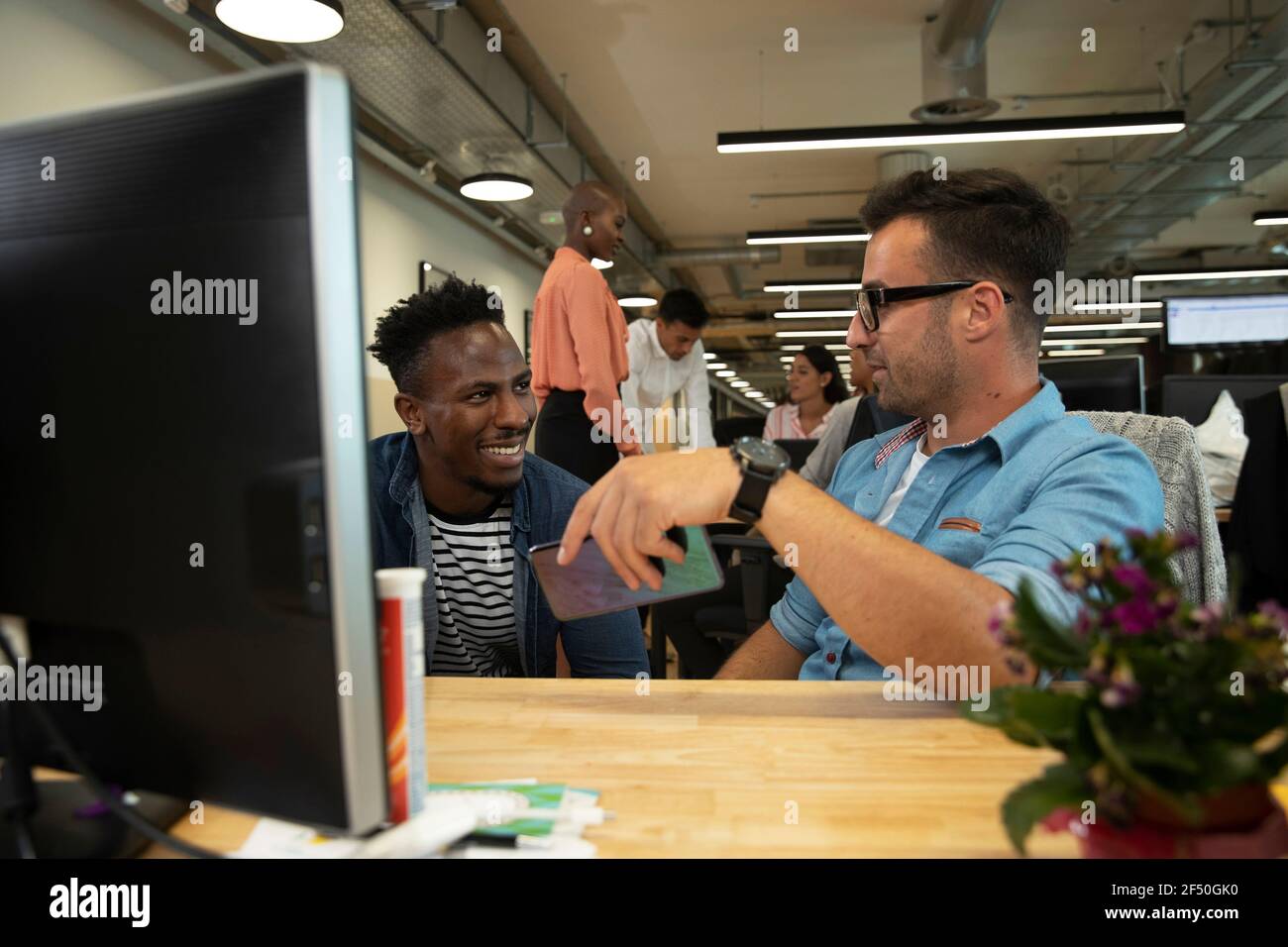 Businessmen talking at computer in office Stock Photo