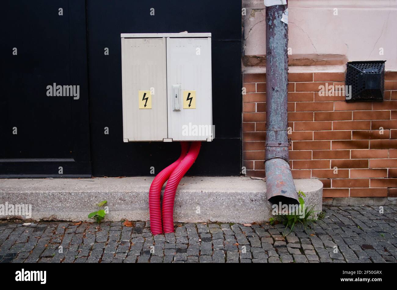High voltage electricity box and on the street. Storm tubes on the wall. Stock Photo