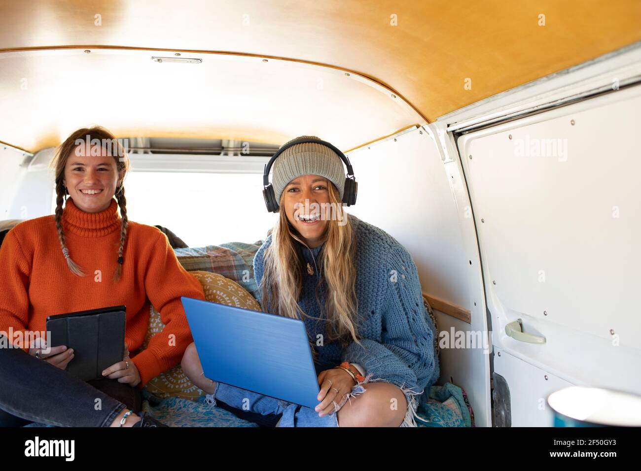 Portrait happy young women friends using technology in camper van Stock Photo