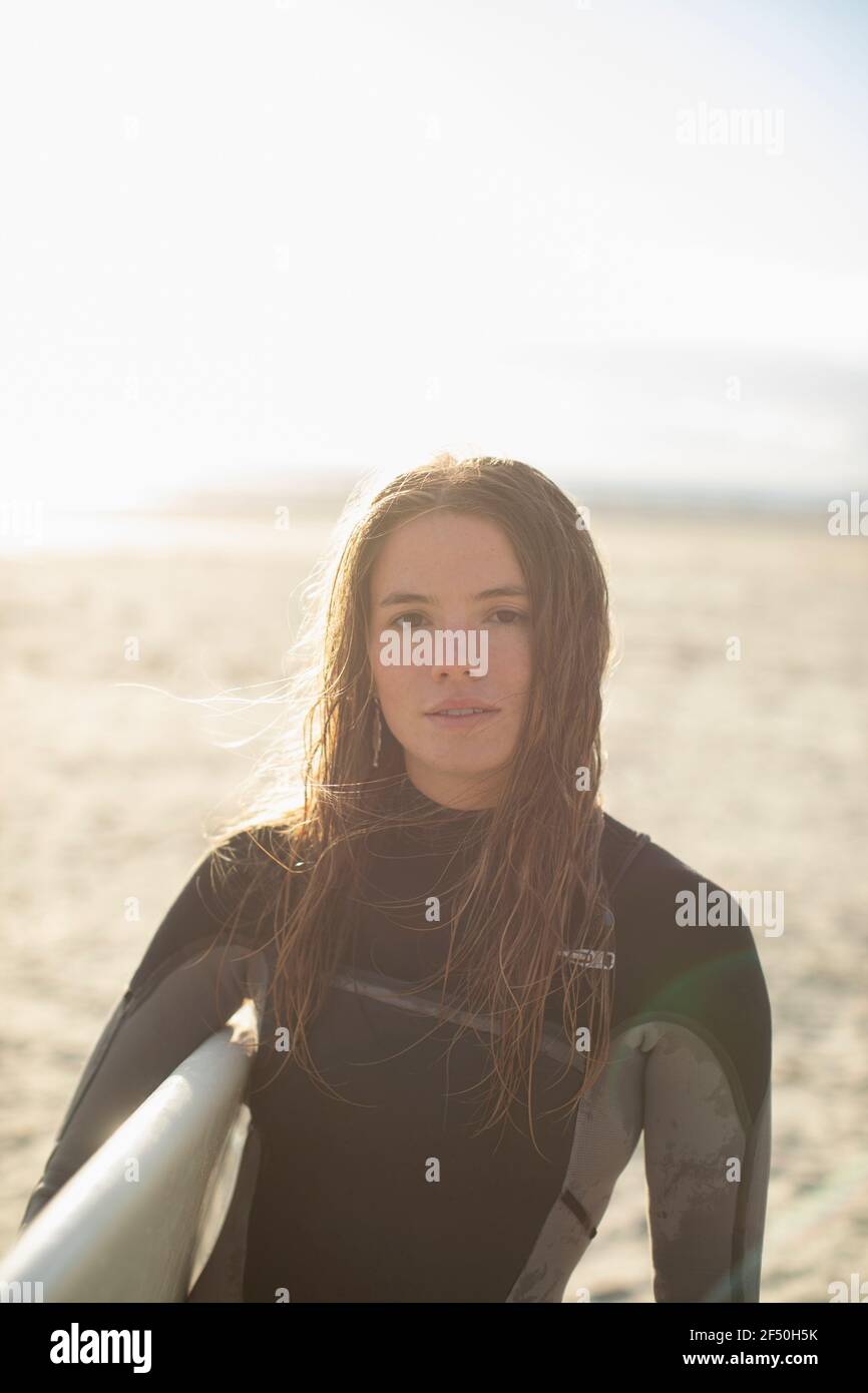 Portrait beautiful young female surfer with wet hair on sunny beach Stock Photo