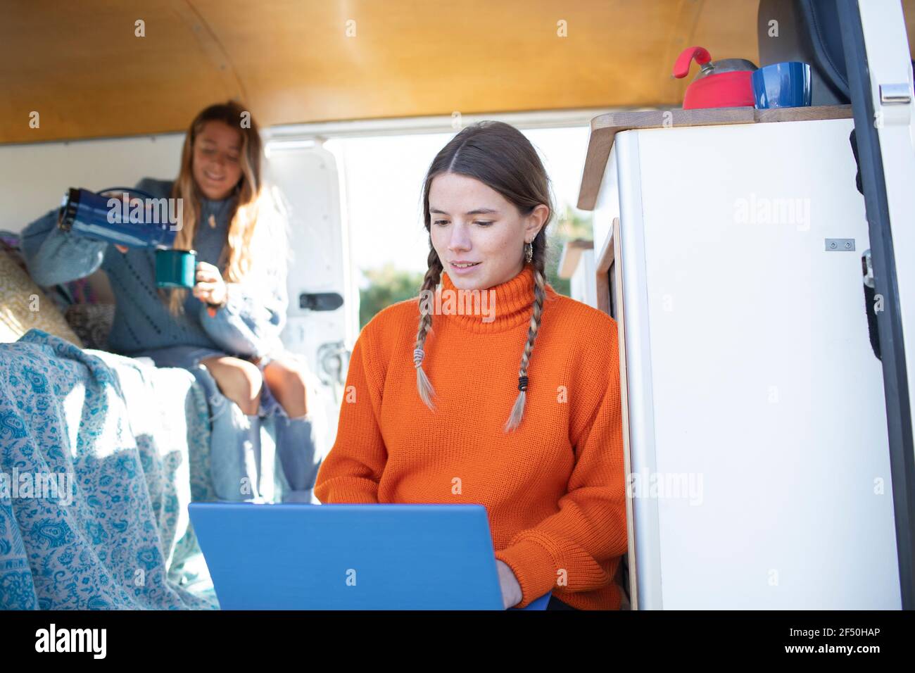 Young women friends with laptop and coffee inside camper van Stock Photo