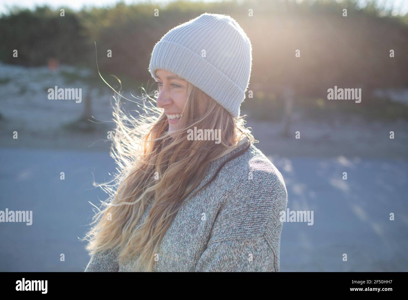 Beautiful happy young woman in knit hat on sunny beach Stock Photo