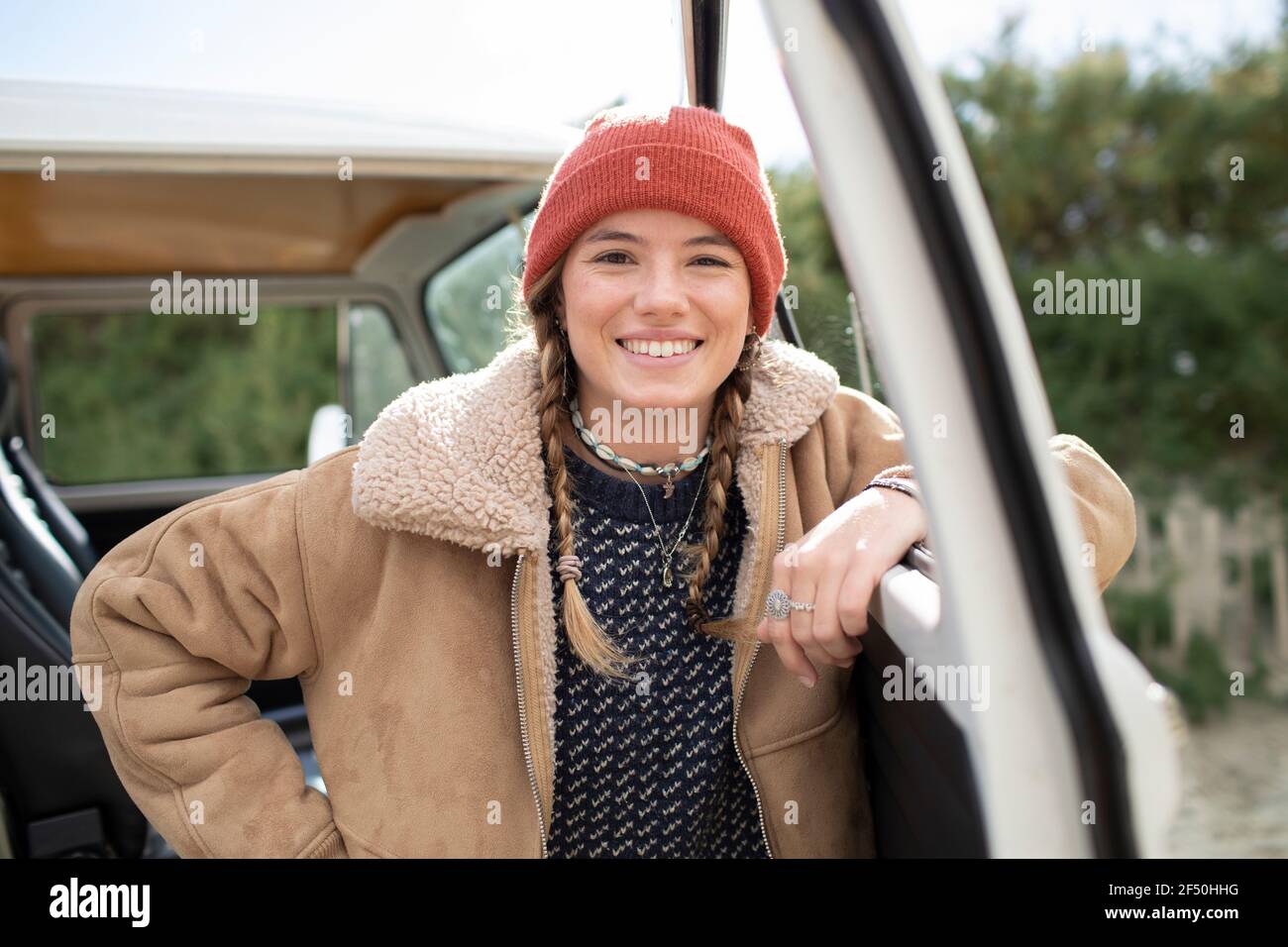 Portrait happy young woman in knit hat at camper van doorway Stock Photo