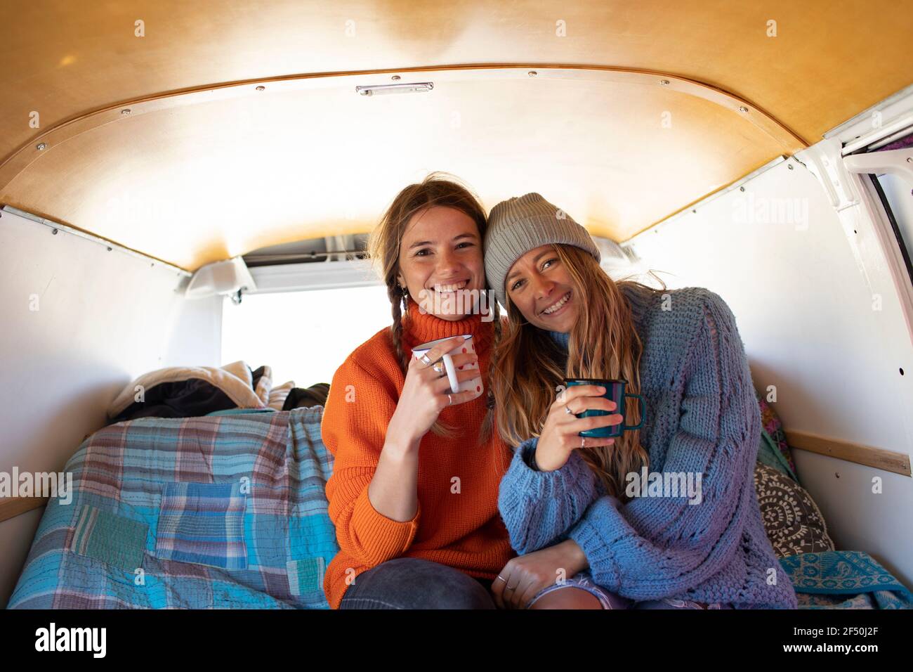 Portrait happy young women friends drinking tea in camper van Stock Photo