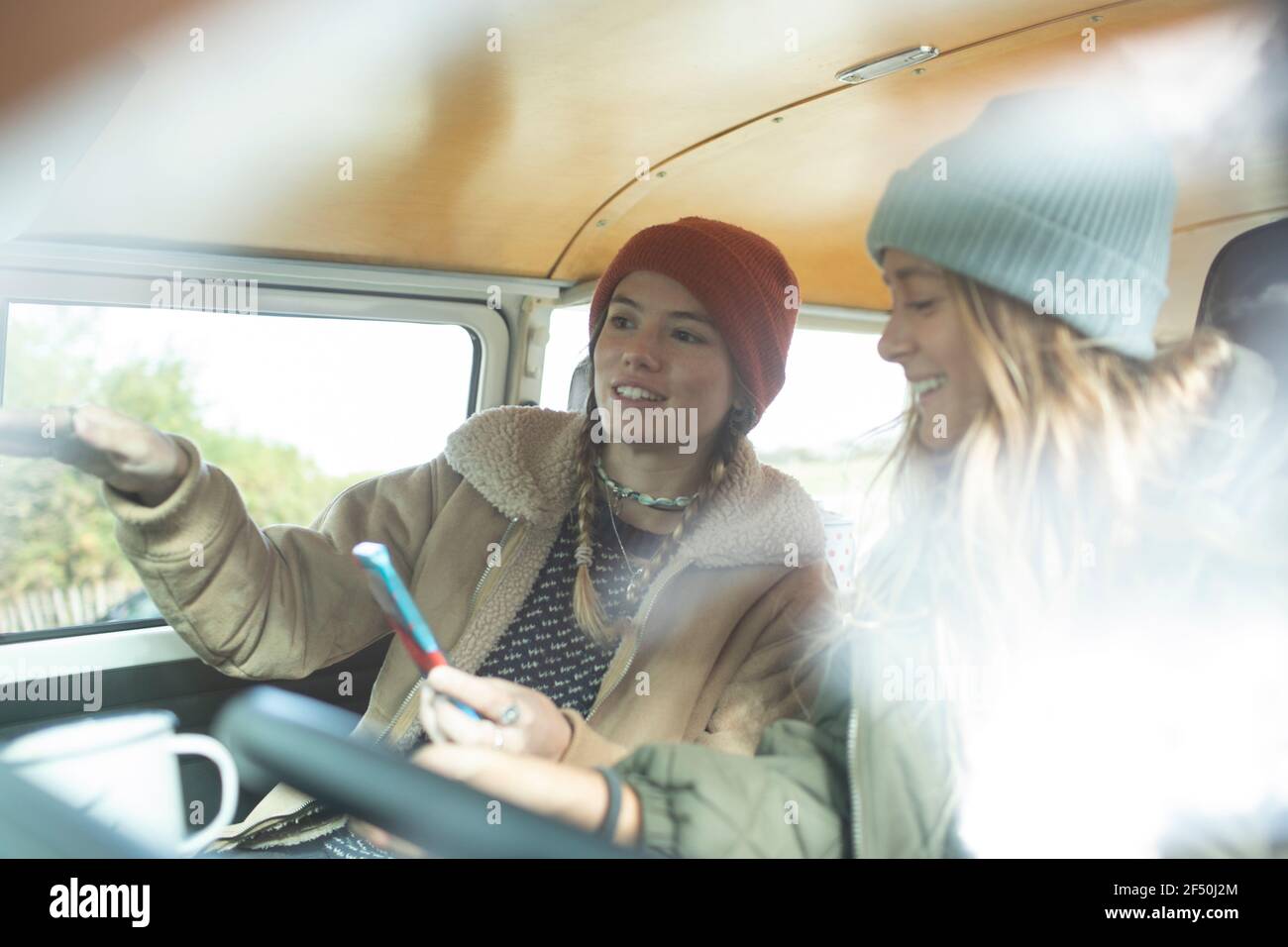 Young women friends using smart phone inside camper van Stock Photo
